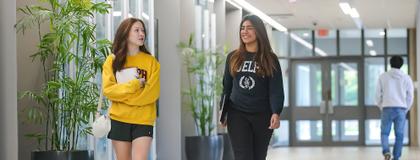 Two students walk together while chatting and laughing in the engineering building.