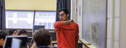 A graduate student looking out at the class of undergraduate physics students during a lab.