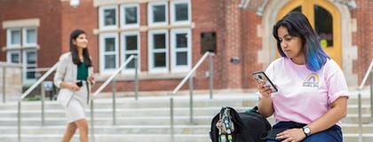 female U of G student sitting and looking at her smartphone