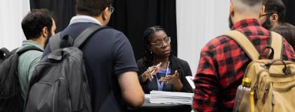 A career advisor gives advice to a group of students at a job fair.