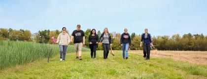 Six people walking towards the camera in a field.