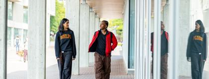 Two students walking and talking on campus outside the Thornbrough building.
