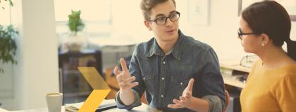 Man and woman having a conversation in a workplace setting.
