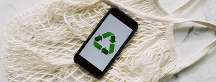 Recycling symbol on a phone, placed on top of a reusable shopping bad