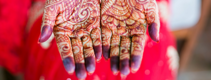 A person holds out their hands to show intricate henna designs on their palms.