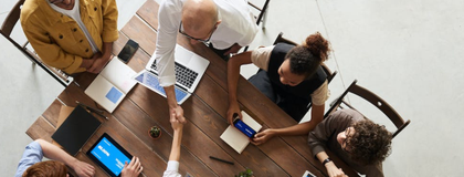 photo of employee shaking hands with another employee at a table