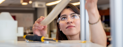 Female student adjusting some tubing on a metal structure
