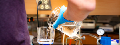 someone pours into a beaker