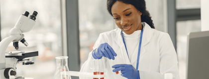 Lab technician working at a desk with a microscope and test tubes