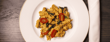 Pasta salad on a white plate with a roll up