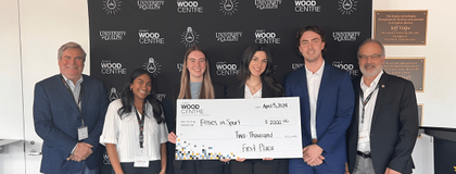 4 students standing with 2 professors and large cheque