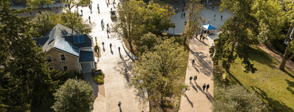 An aerial shot of U of G's campus featuring buildings and red brick stone pathways surrounded by green trees.