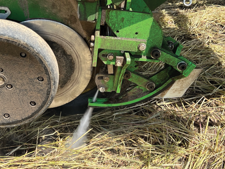 Close-up of a tractor using a water jet attachment for planting in a field.