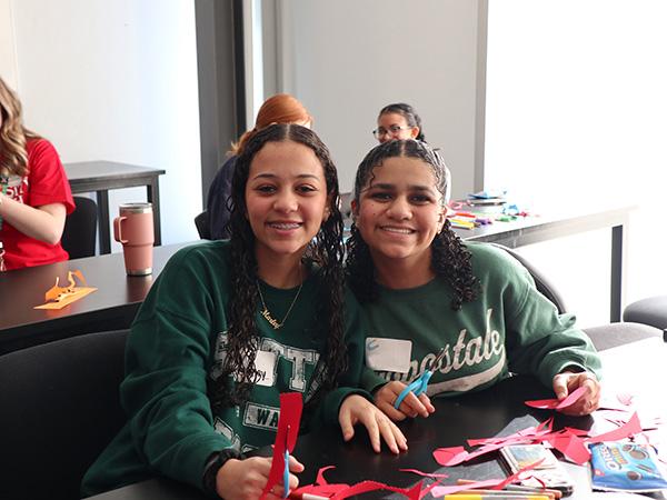 two seated girls smiling, doing an activity