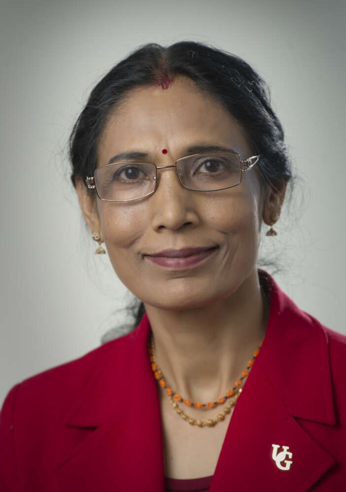 Professor smiling at camera with bright red blazer on.