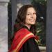 Grace smiles wearing a red graduation hood