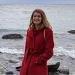 Danielle in red coat in front of lake with rocks