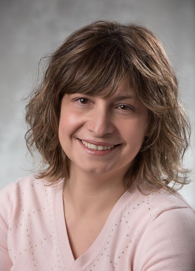 Woman head shot, wearing pink v-neck sweater