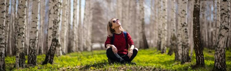 a student sits in the forest looking at the canopy