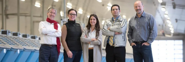 A group of five diverse researchers pose in a dairy barn.