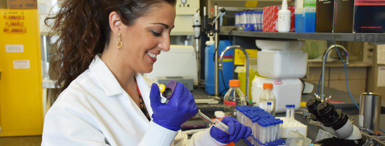 a lab technician working on a sample, wearing a labcoat