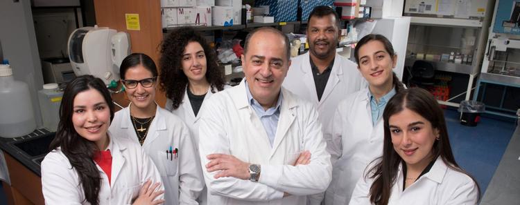 Members of the Sharif Lab standing together in white lab coats, smiling at the camera.
