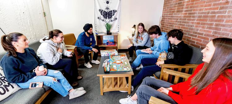Students talking and playing boardgame in the residence lounge
