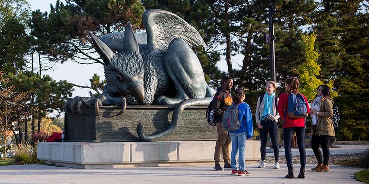 A group of U of G students standing in front of the Gryphon statue