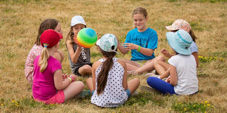 A group of children sitting in a circle playing outside.