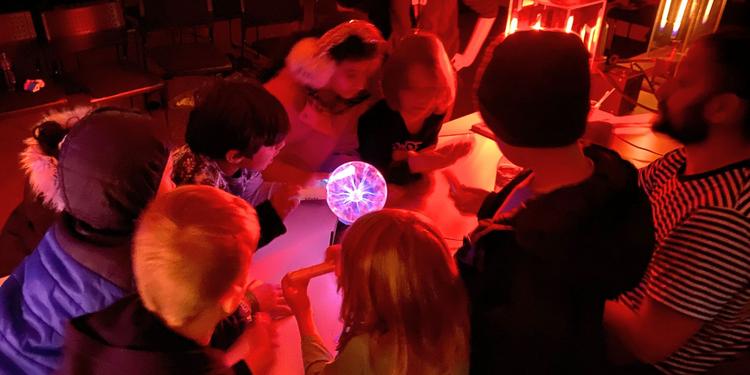 A group of children huddled around a plasma ball at the Creative Encounters camp.