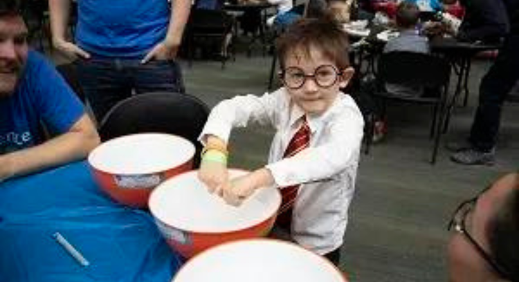 Kid with a mixing bowl at a Let's Talk Science event.