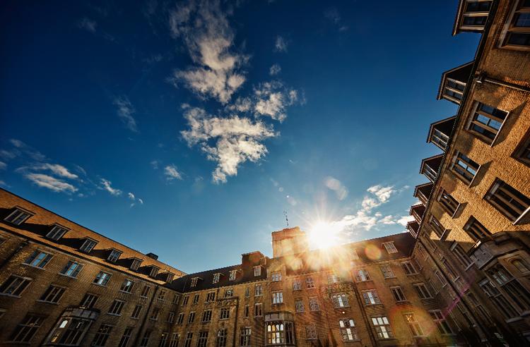 A picture of Johnston Hall, blue skies with the sun rising over the building.