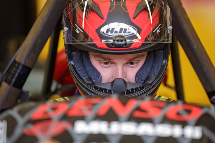 student wearing a helmet, sitting in the Gryphon racecar