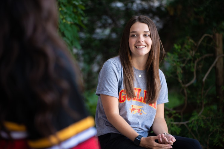 a student wearing a Guelph Gryphons t-shirt smiles in conversation with another student outdoors