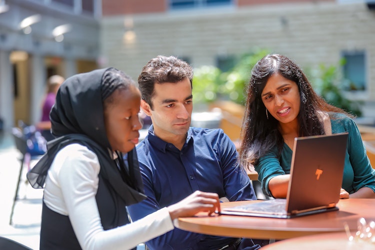 Dr. Ayesha Ali and two Master of Data Science students working on computer