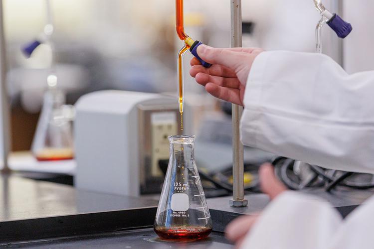 a liquid being poured into a beaker in a science lab