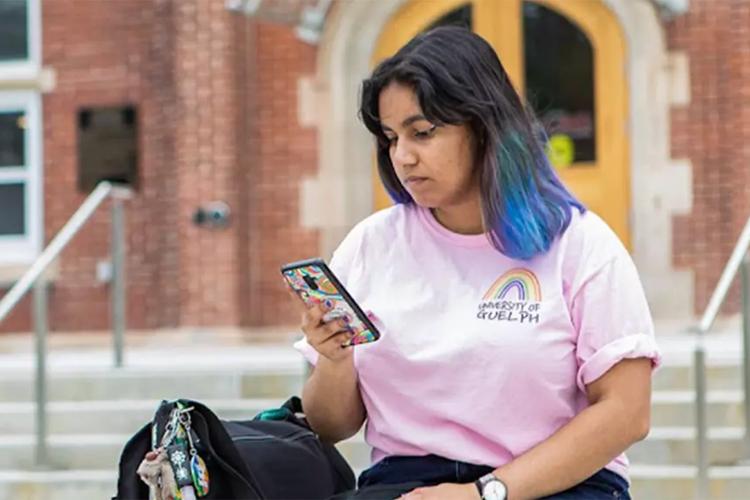 Female student sitting outside looking at her smartphone