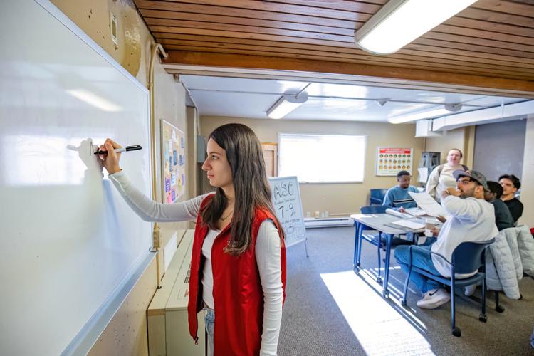 Residence Life Staff member writing on the whiteboard and students are sitting behind and looking at the board
