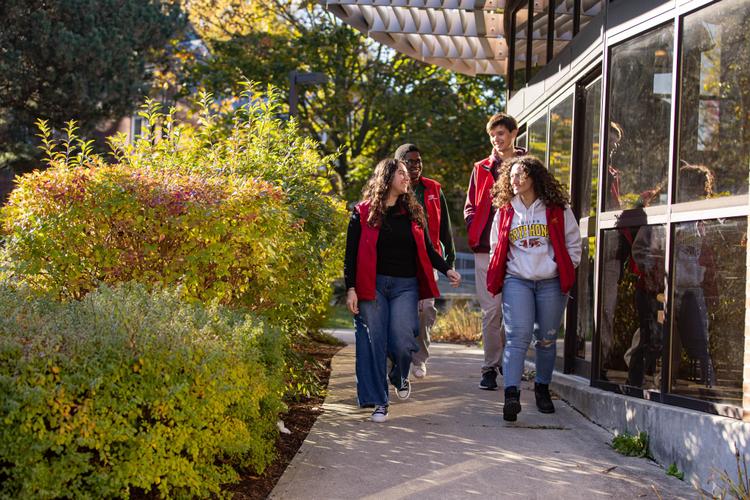 Four Residence Life Staff members in the red vest walking outside the LA residence