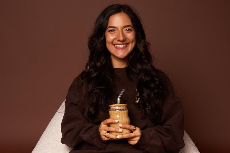 An image of a person smiling holding a coffee cup