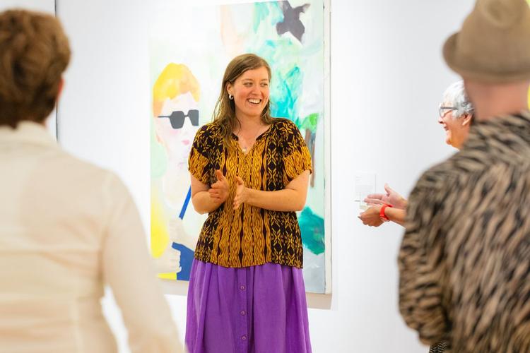 Individuals talking with Samuelle Grande at her art exhibit.