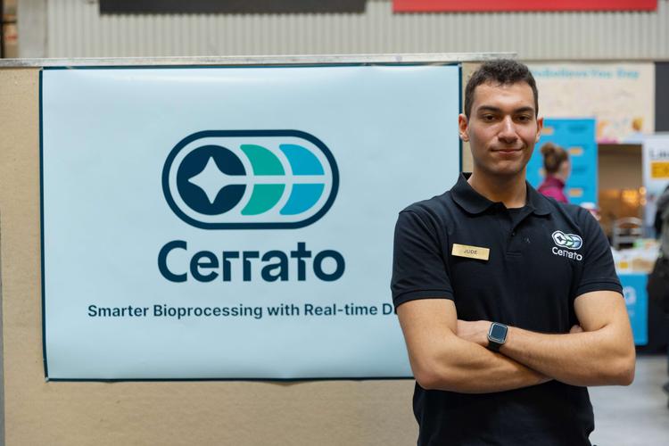 A person smiling at the camera with their arms crossed and a banner behind them with the text 'Cerrato'