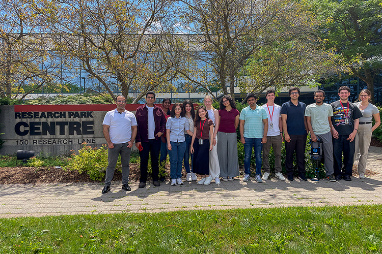Canada Cyber Foundry researchers and students stand as a group outside research park buildings smiling at camera
