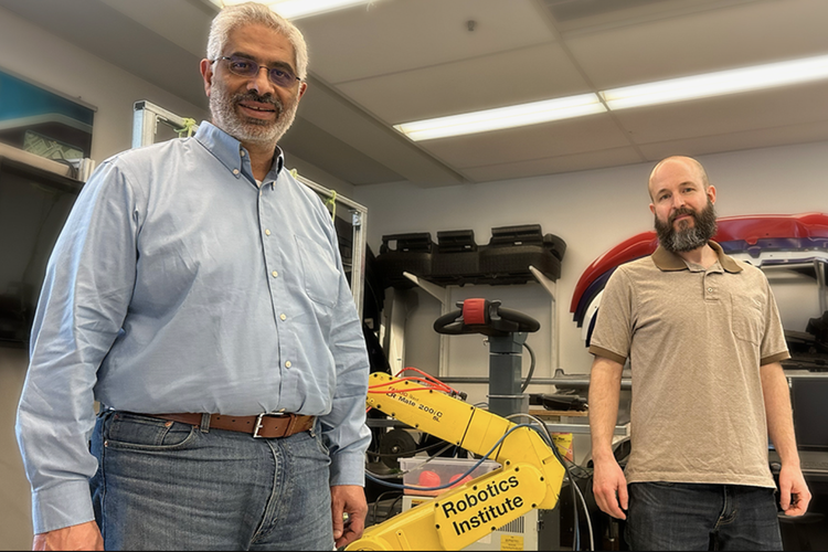 Robotics institute researchers stand in front of robot arm