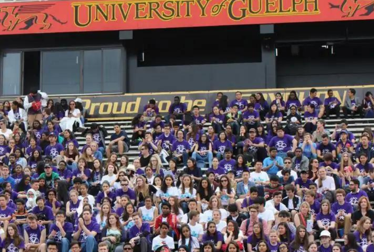 Large group of high school students in purple shirts sitting on bleachers at the University of Guelph for a Battle STEM event.