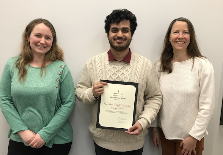 Abdus holds his certificate, posing and smiling beside his two nominators, Jodie and Sarah.