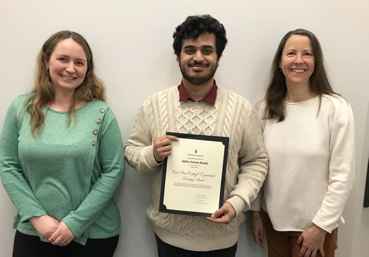 Abdus holds his certificate, posing and smiling beside his two nominators, Jodie and Sarah.