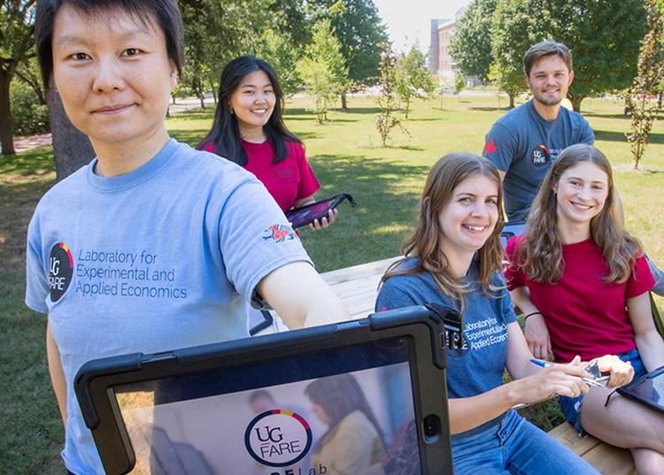 students in the fare lab with professor holding a tablet that says fare Lab