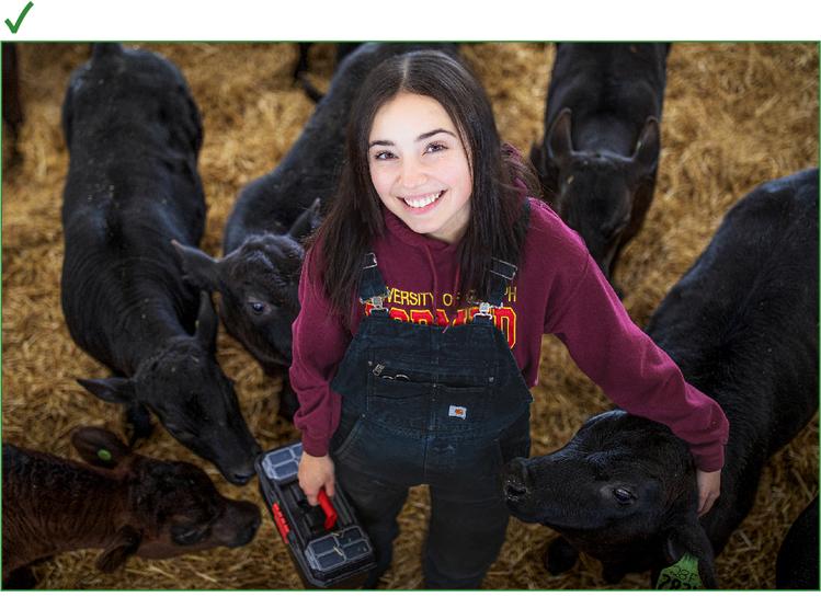 Student smiling at the camera while surrounded by cows.