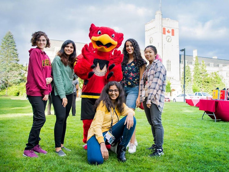 students posing with Gryph mascot in front of Johnston Hall